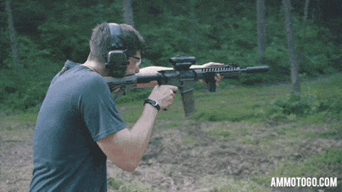A man shooting an AR 15 rifle with a silencer