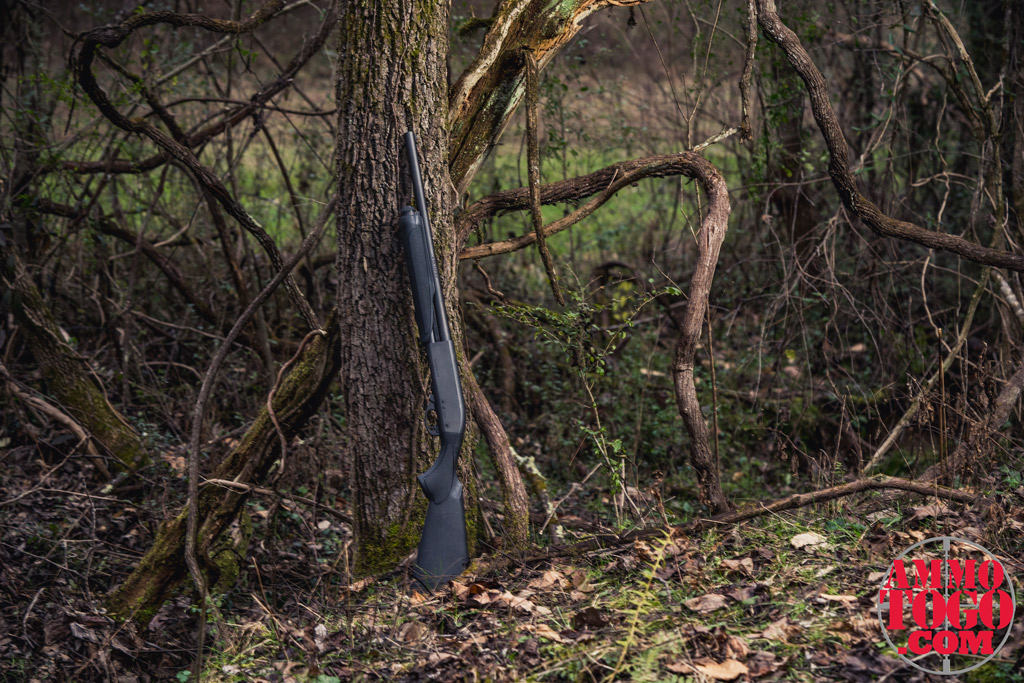 a photo of a 12 gauge remington 870 against a tree outdoors