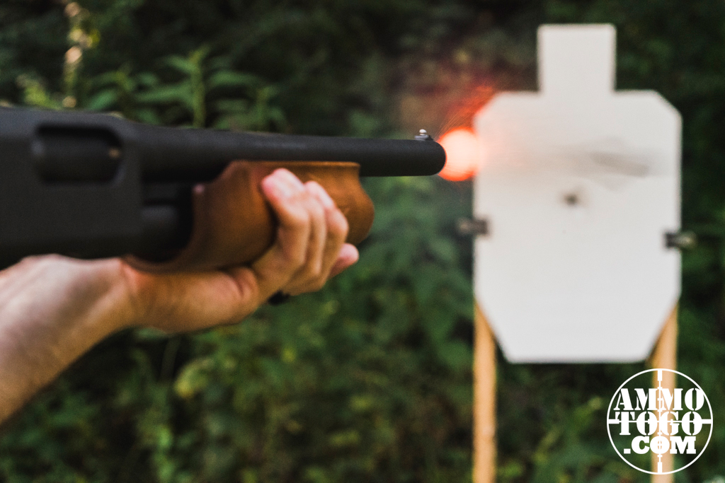 Firing a 12 gauge shotgun toward a paper target at a shooting range