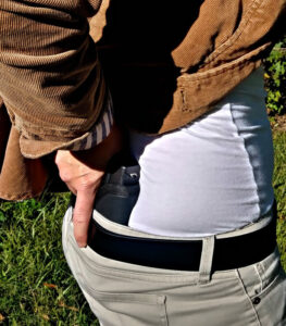 Demonstrating a concealed carry gun carried in the small of your back.