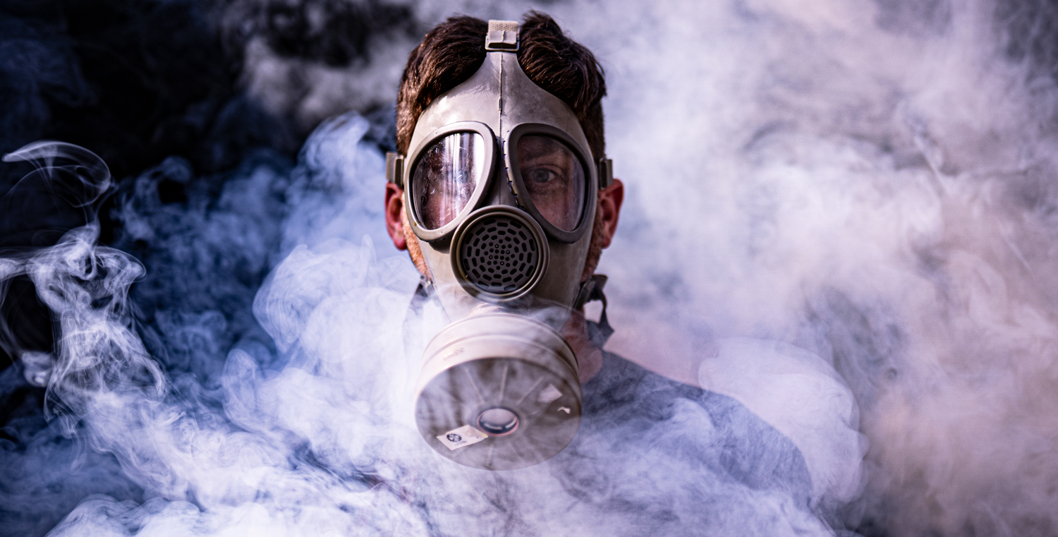author wearing a gas mask amid a smoke field